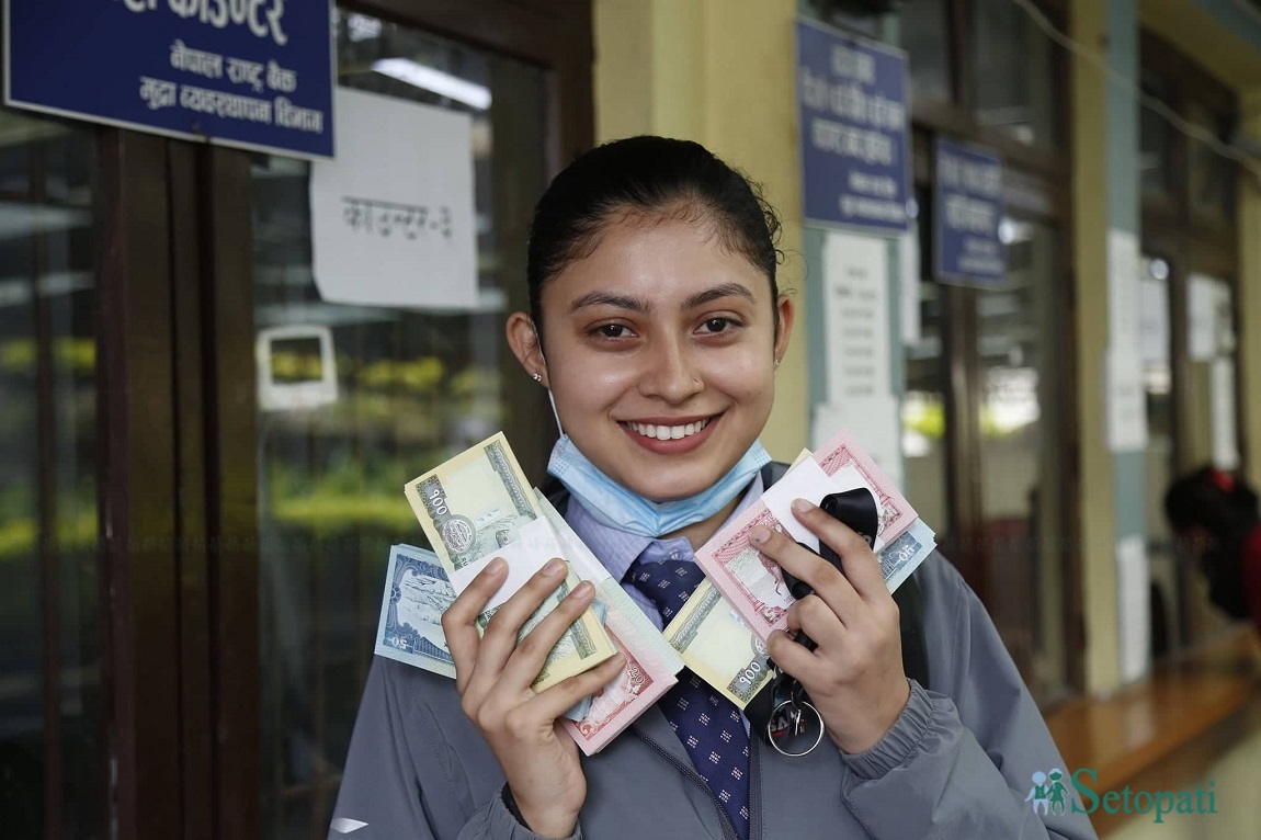 नेपाल राष्ट्र बैंकले आजदेखि दिन थालेको नयाँ नोट देखाउँदै एक युवती। तस्बिरः नवीनबाबु गुरूङ/सेतोपाटी