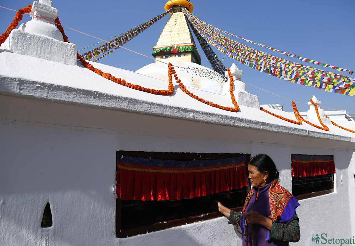 काठमाडौँको बौद्धमा माने घुमाएर कोरा गर्दै एक महिला।   तस्विर : नवीनबाबु गुरुङ/सेतोपाटी