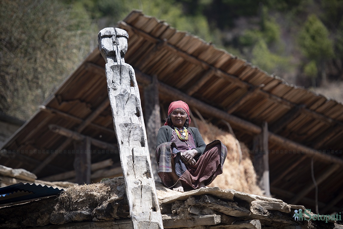 मुगुको मुर्मा गाउँमा आफ्नो घरको आँगनमा बसेर मुस्कुराउँदै एक वृद्धा। तस्बिर: निशा भण्डारी/ सेतोपाटी