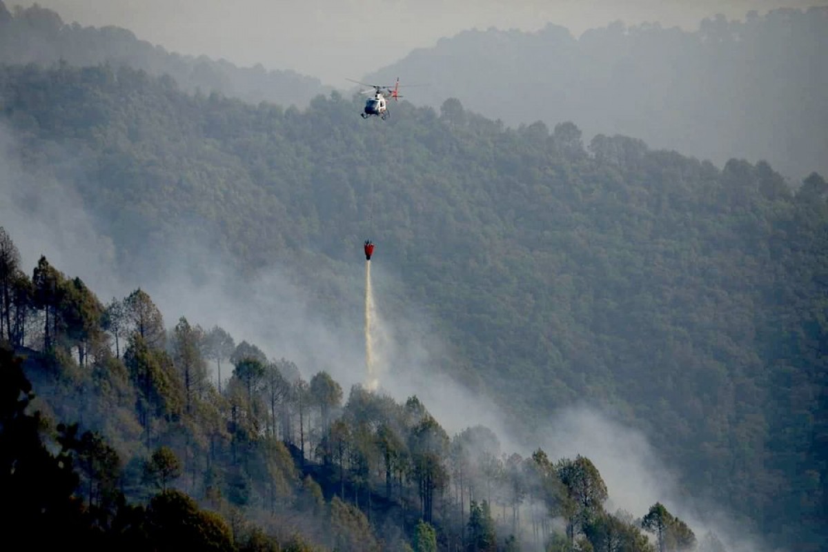 आगो नियन्त्रणका लागि हेलिकप्टरबाट पानी खसाल्दै सिम्रिक एयरको हेलिकप्टर।