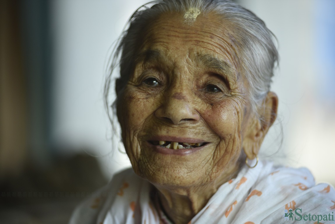 'आमा, हाँस्नुहोस् न !' भन्दा  'मेरो दाँत भाँच्चिएको छ क्या!' भनेर पोज दिँदै कृष्णकुमारी घिमिरे। तस्बिरः नारायण महर्जन/सेतोपाटी