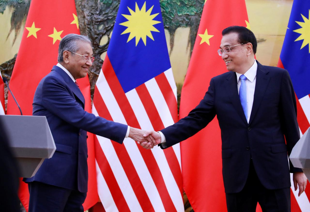 चीन भ्रमणमा रहेका मलेसियाली प्रधानमन्त्री महाथिर समकक्षी ली खछ्याङसँग हात मिलाउँदै।