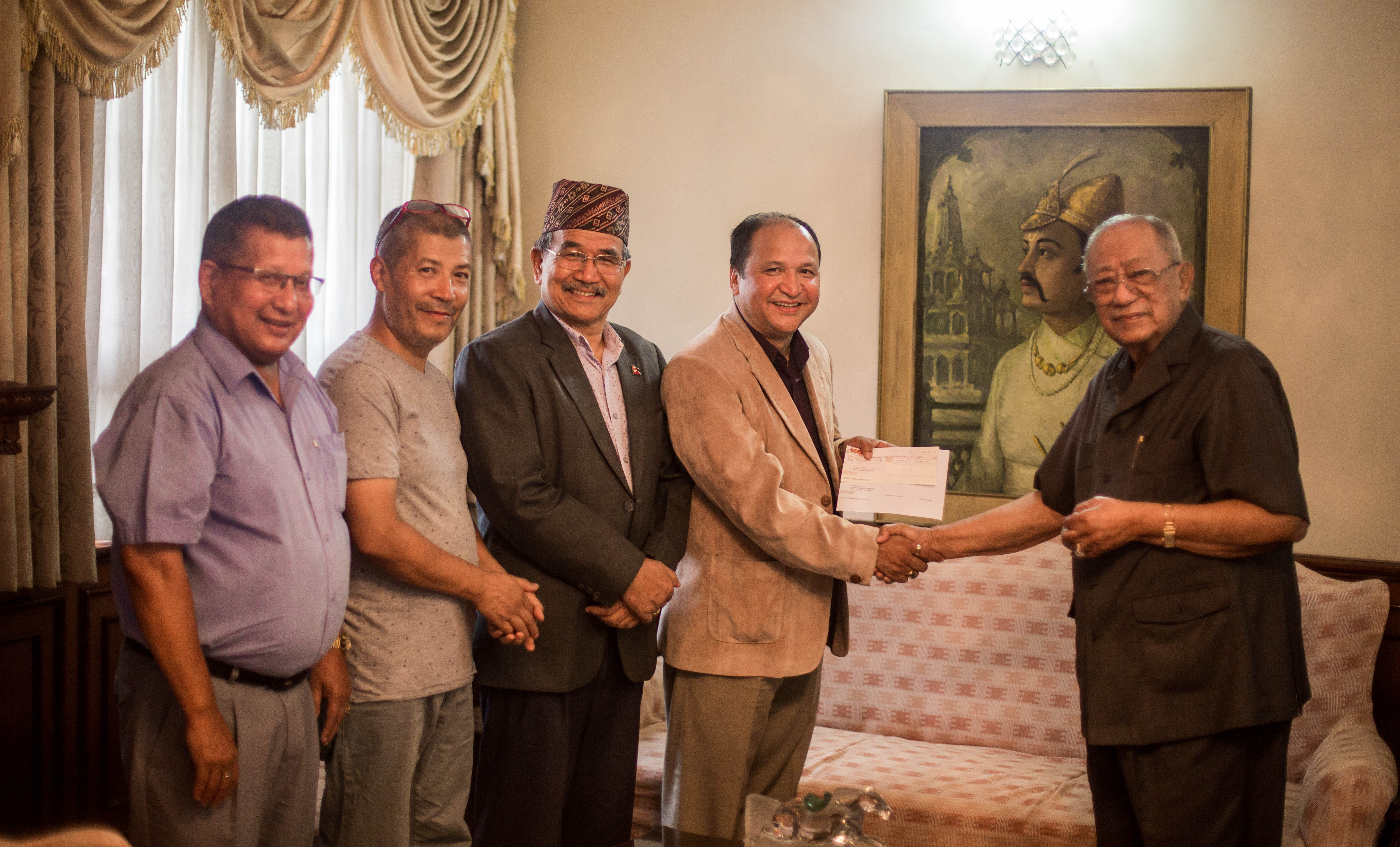 पाटनको भीमसेन मन्दिर पुनर्निर्माणका लागि एक करोड रूपैयाँको चेक हस्तान्तरण गर्दै स्थानीय व्यवसायी बिके श्रेष्ठ (सबभन्दा दायाँ)।