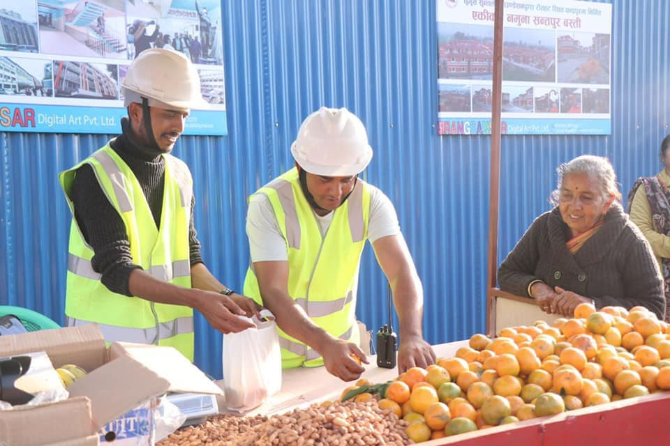 रंगशाला बनाउन सञ्चालन गरेको ठेला पसलमा सुन्तला र बदाम बेच्दै सीताराम कट्टेल 'धुर्मुस'। तस्बिर स्रोत: धुर्मुसको फेसबुक