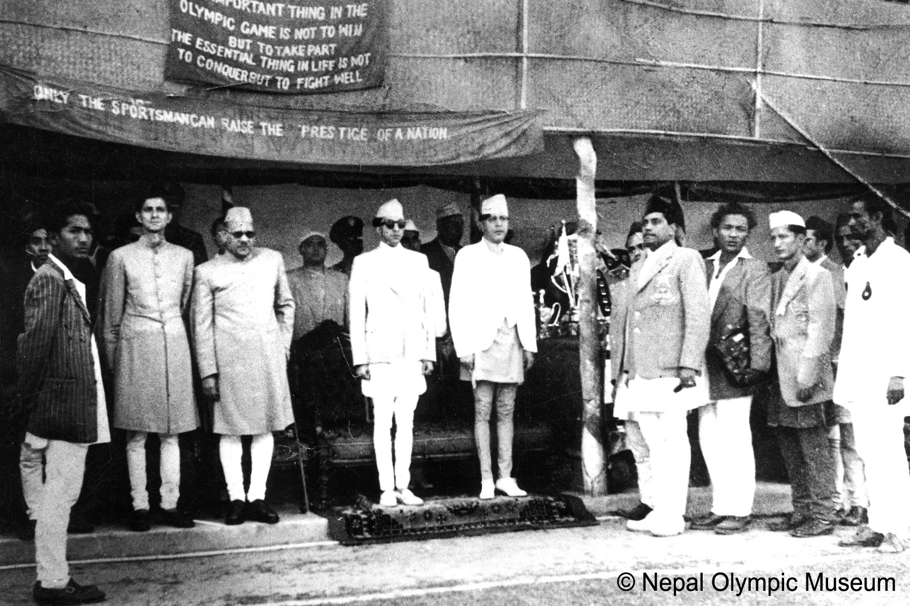सन् १९५२, हेलसिन्की ओलम्पिकमा पर्यवेक्षकका रूपमा सहभागीको बिदाइ कार्यक्रममा बायाँ-दोस्रोबाट तत्कालीन गृहमन्त्री विपी कोइराला, प्रथम भारतीय राजदूत चण्डेश्वरप्रसाद सिंह, युवराज महेन्द्र, राजा त्रिभुवन, नरशमशेर जबरा र कृष्णबहादुर बर्मा (सेतो टोपी)।