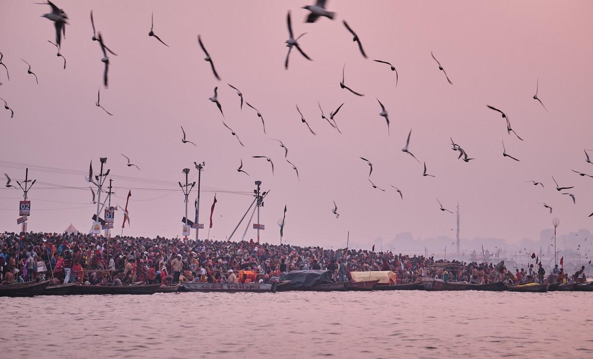 कुम्भ मेलाका क्रममा गंगा नदी किनार प्रार्थना गरिरहेका तीर्थालुहरूको भीडमाथिबाट उडिरहेका चराको बथान। तस्बिर:  श्रीराम वित्तलमूर्ति/रेस्ट अफ वर्ल्ड