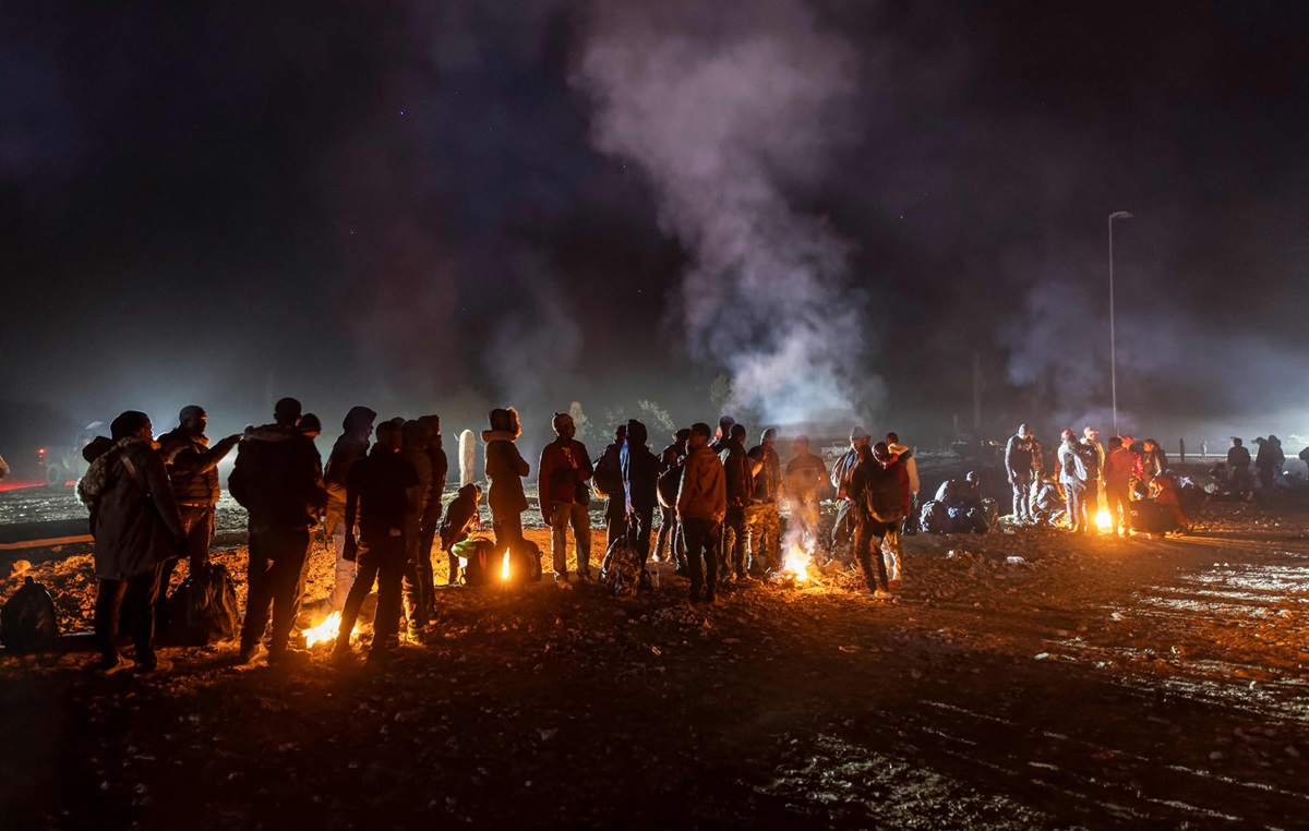 सन् २०२३ डिसेम्बर ६ मा अमेरिका-मेक्सिको सीमामा रहेको एरिजोनामा अवैध रूपले अमेरिका प्रवेश गरेकाहरू न्यानो हुन आगो ताप्दै। तस्बिर: जोन मोर/एएफपी