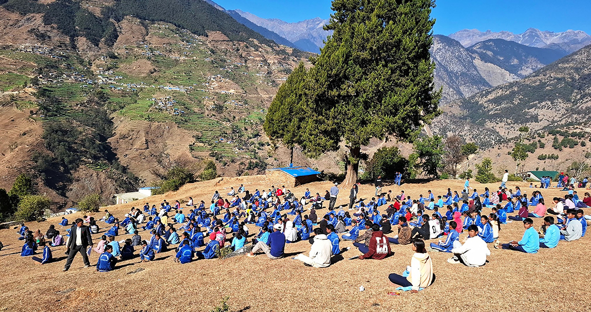 बारेकोट गाउँपालिका–५ स्थित सरस्वती माध्यमिक विद्यालयका विद्यार्थी घाममा परीक्षा दिँदै । अत्यधिक चिसो बढेपछि विद्यालय परिसरको चौरमा घाममा बसेर  उनीहरुले परीक्षा दिएका हुन् । तस्बिरः हेमन्त केसी/रासस