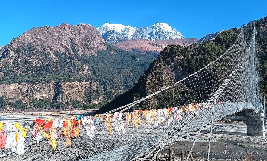 मुस्ताङको थासाङ गाउँपालिका-२ स्थित कालीगण्डकी नदीमाथि अवस्थित नवनिर्मित झोलुङ्गेपुल र पृष्ठभूमिमा निलगिरि हिमाल। यहाँबाट देखिने दृश्य मुस्ताङ घुम्न आउने आन्तरिक तथा वाह्य पर्यटकका लागि लोभलाग्दो छ। तस्बिरः सुशीलबाबु थकाली/ रासस