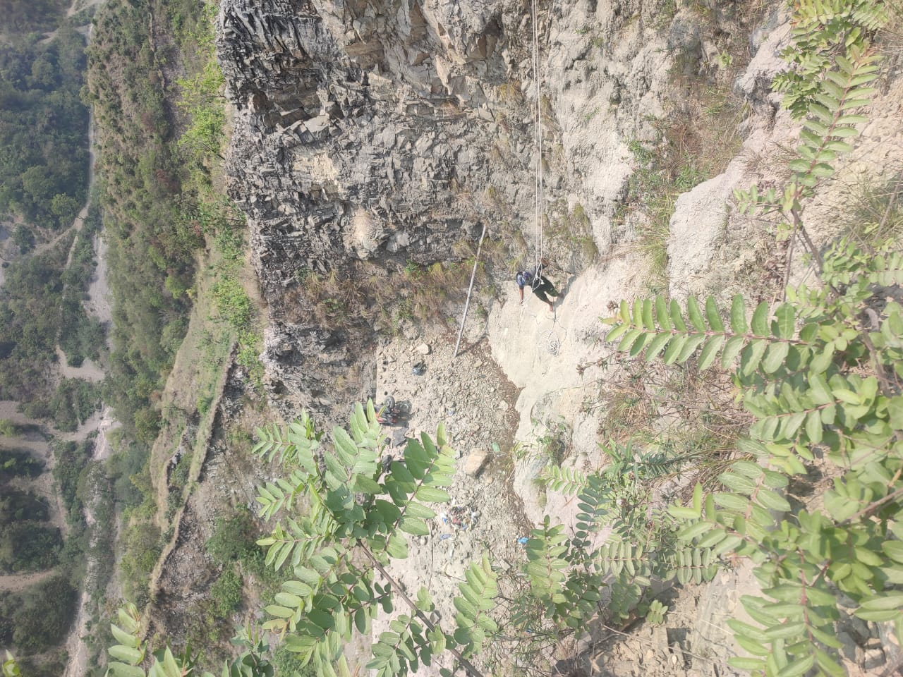 भीरमा खसेको स्कुटर र उद्धारका लागि खटिएका प्रहरी। स्कुटर खसेको स्थानबाट पनि अझै तल चालक खसेका छन्।